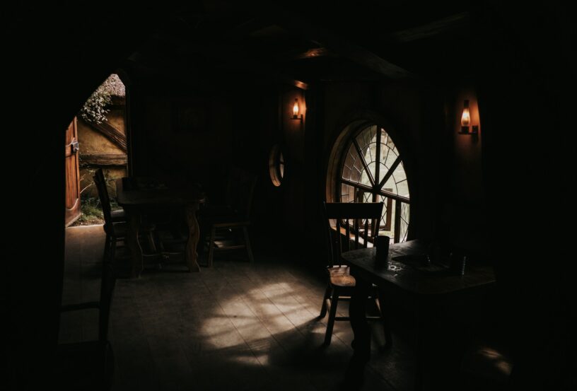 Open door inside a small cottage with a table and stool near the window