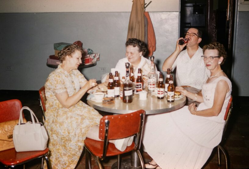 Vintage photograph of friends gathered around a table, representing the personalities spirits carry from life