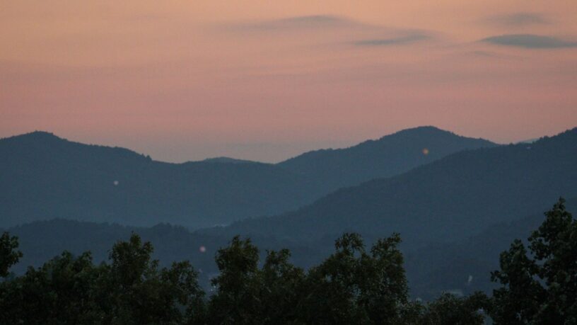 Blue Ridge Mountains in North Carolina at dusk with faint mysterious lights appearing above the distant ridgeline