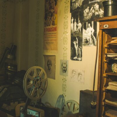 Dimly lit historic room with antique furnishings, shelves, and warm lighting