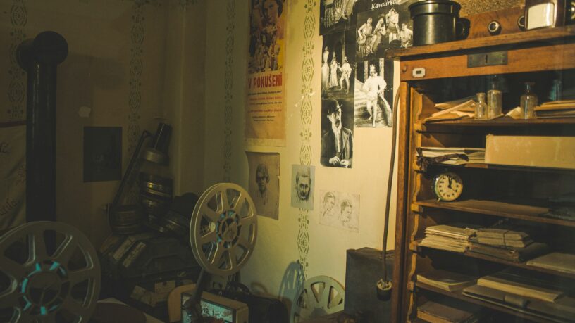 Dimly lit historic room with antique furnishings, shelves, and warm lighting