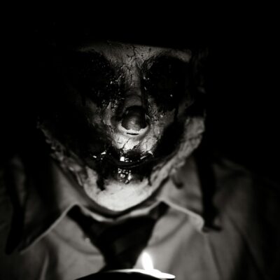 Shadowed human figure with a distorted face emerging from darkness