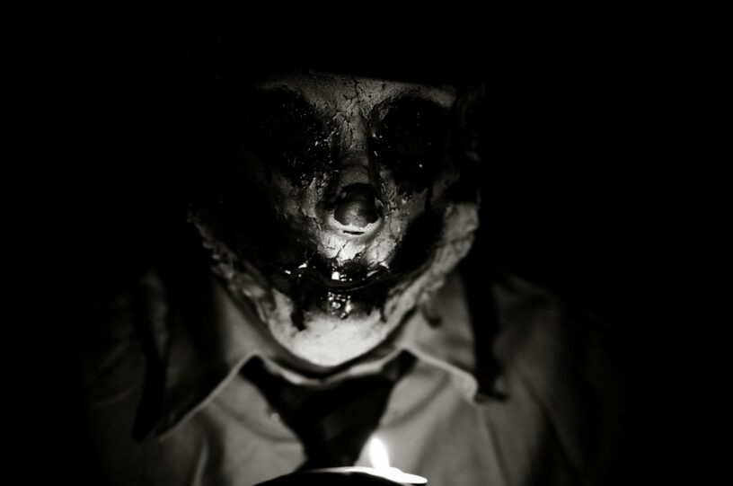 Shadowed human figure with a distorted face emerging from darkness